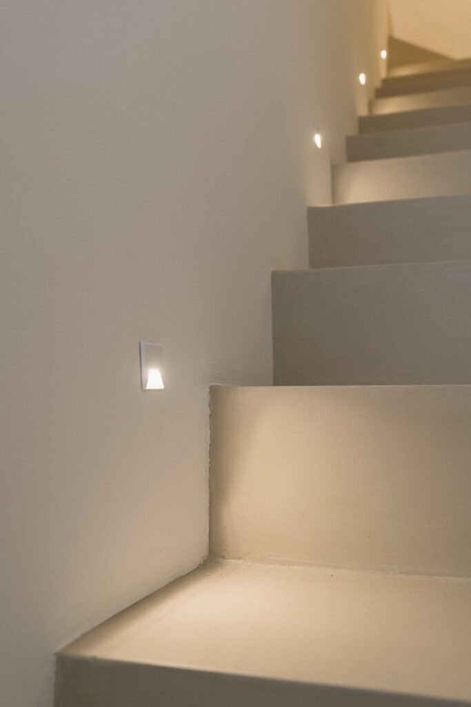 Escalera moderna de hormigón con luces LED empotradas en la pared, iluminando cada peldaño.