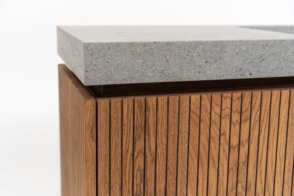Mueble con superficie de hormigón gris y base de madera con listones verticales.