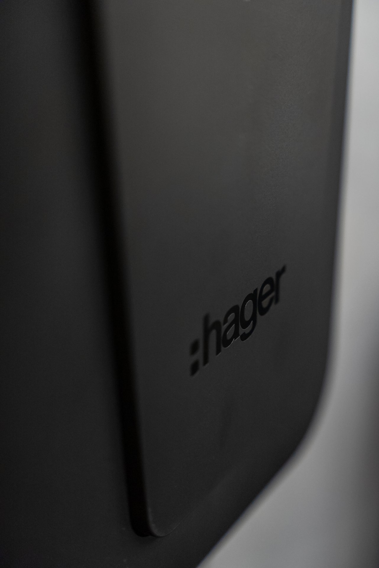 Logo de Hager en relieve sobre una superficie oscura y mate.