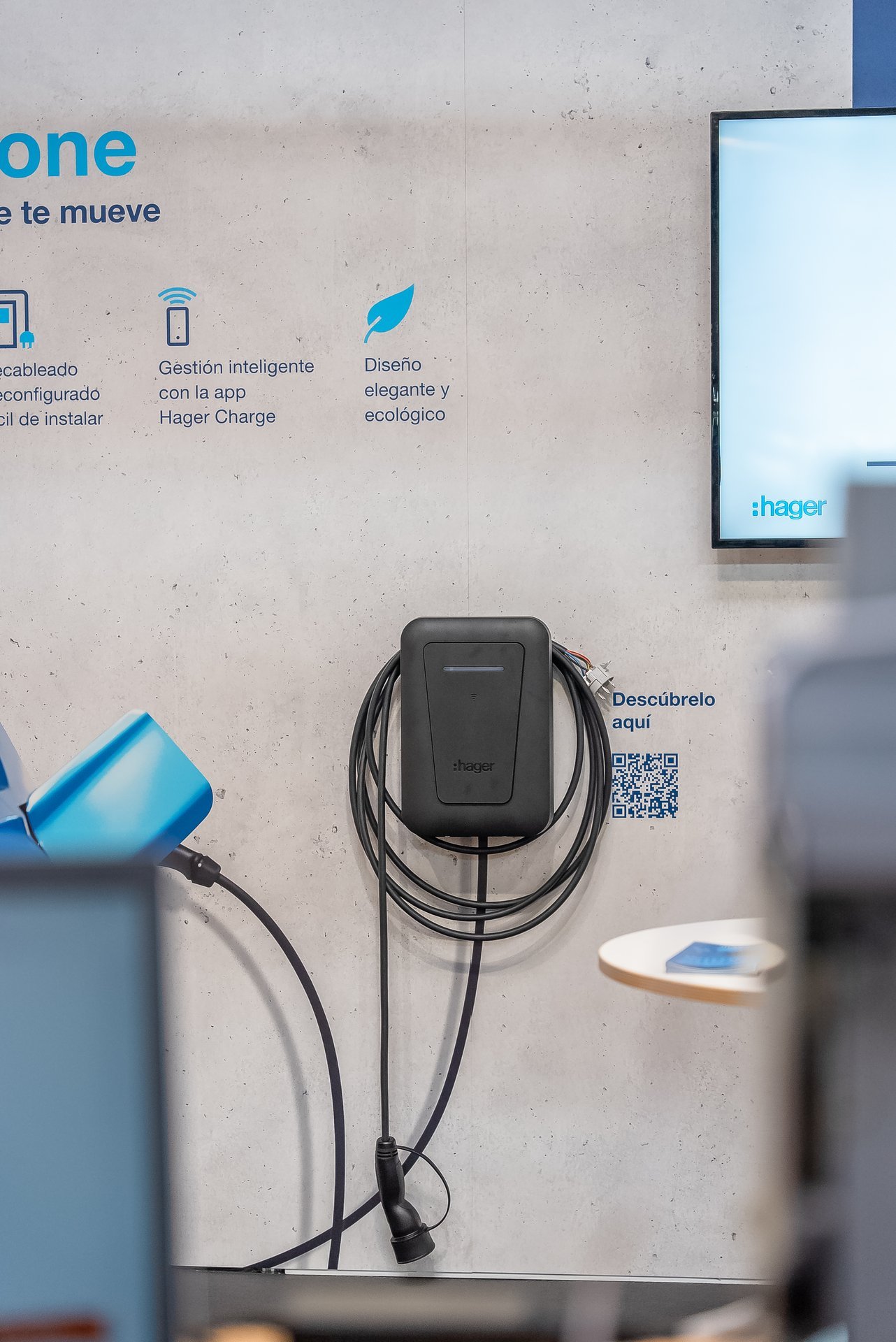 Punto de recarga Hager para vehículos eléctricos en Efintec. Wallbox negro con cables, texto sobre gestión inteligente y diseño ecológico.