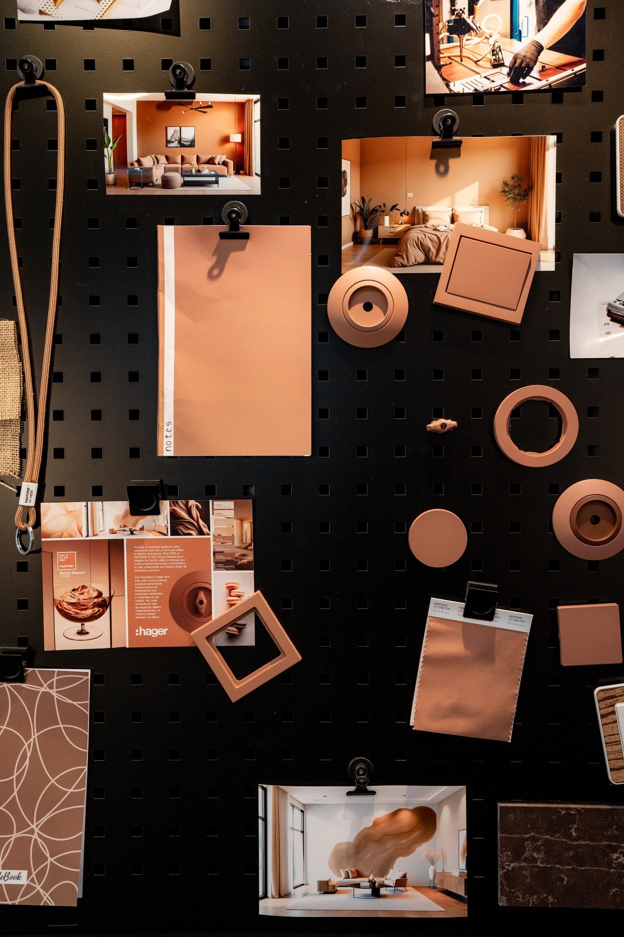 Tablero negro con fotos de interiores, muestras de color terracota y productos eléctricos Hager (interruptores, enchufes) en la misma gama.