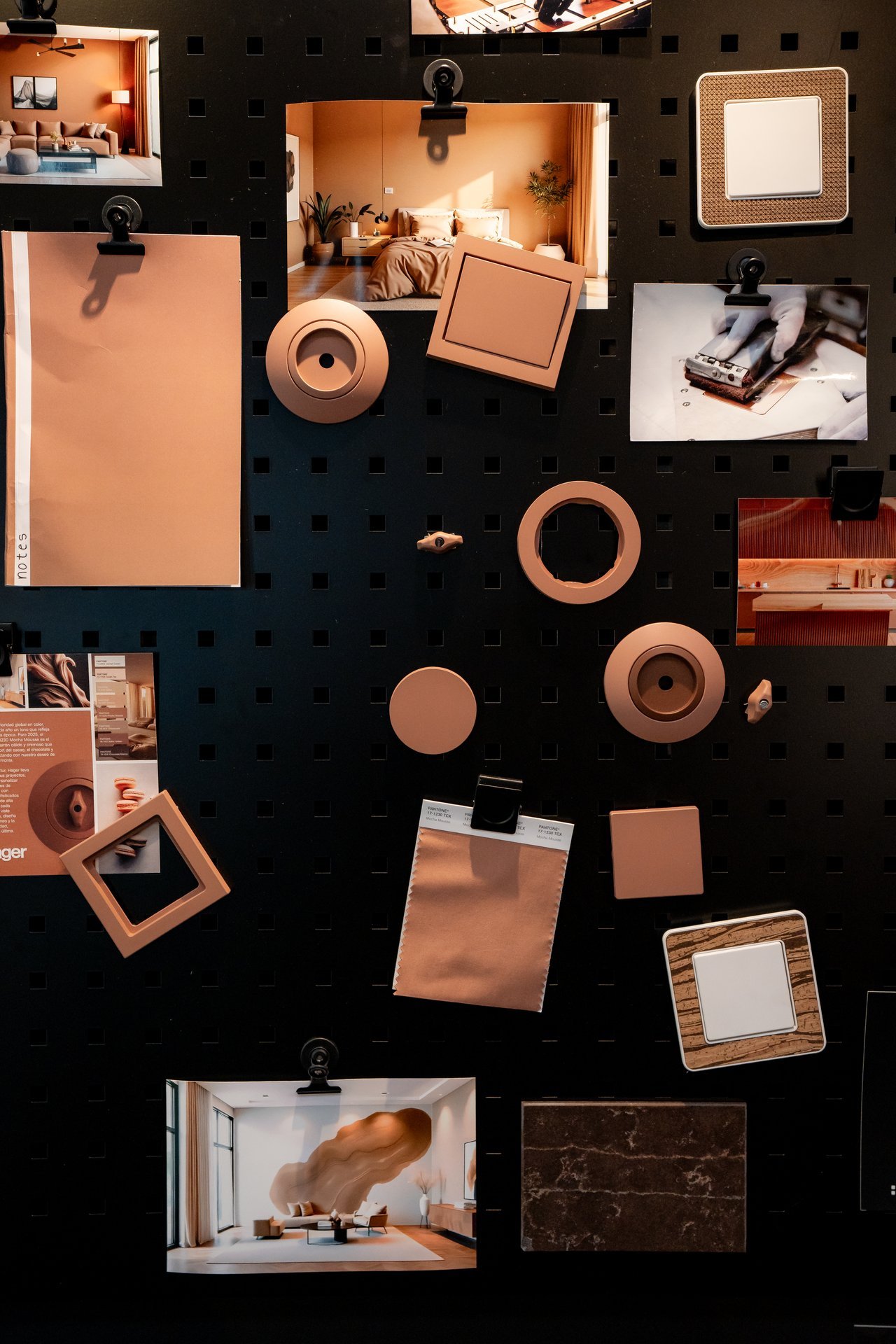 Tablero con fotos de interiores cálidos, muestras de color terracota y mecanismos eléctricos Hager: interruptores, enchufes y acabados.