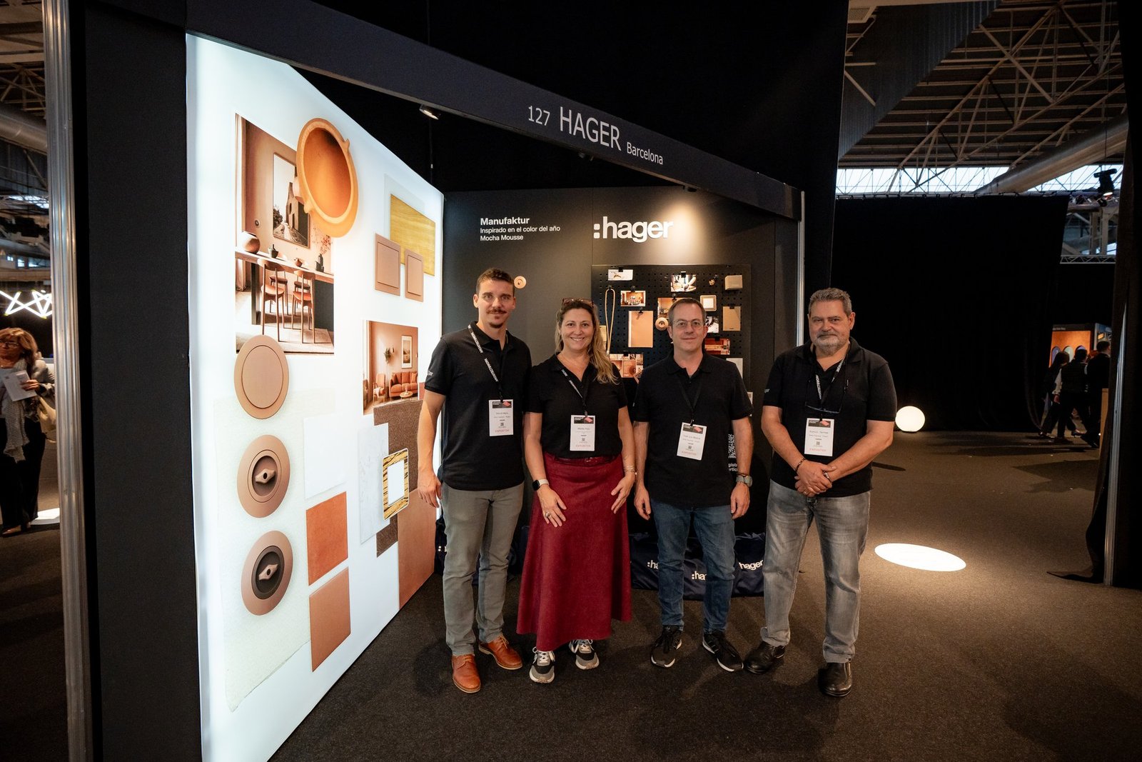 Equipo de Hager posa en su stand de Architect & Work. Muestran productos y diseño interior con tonos cálidos.