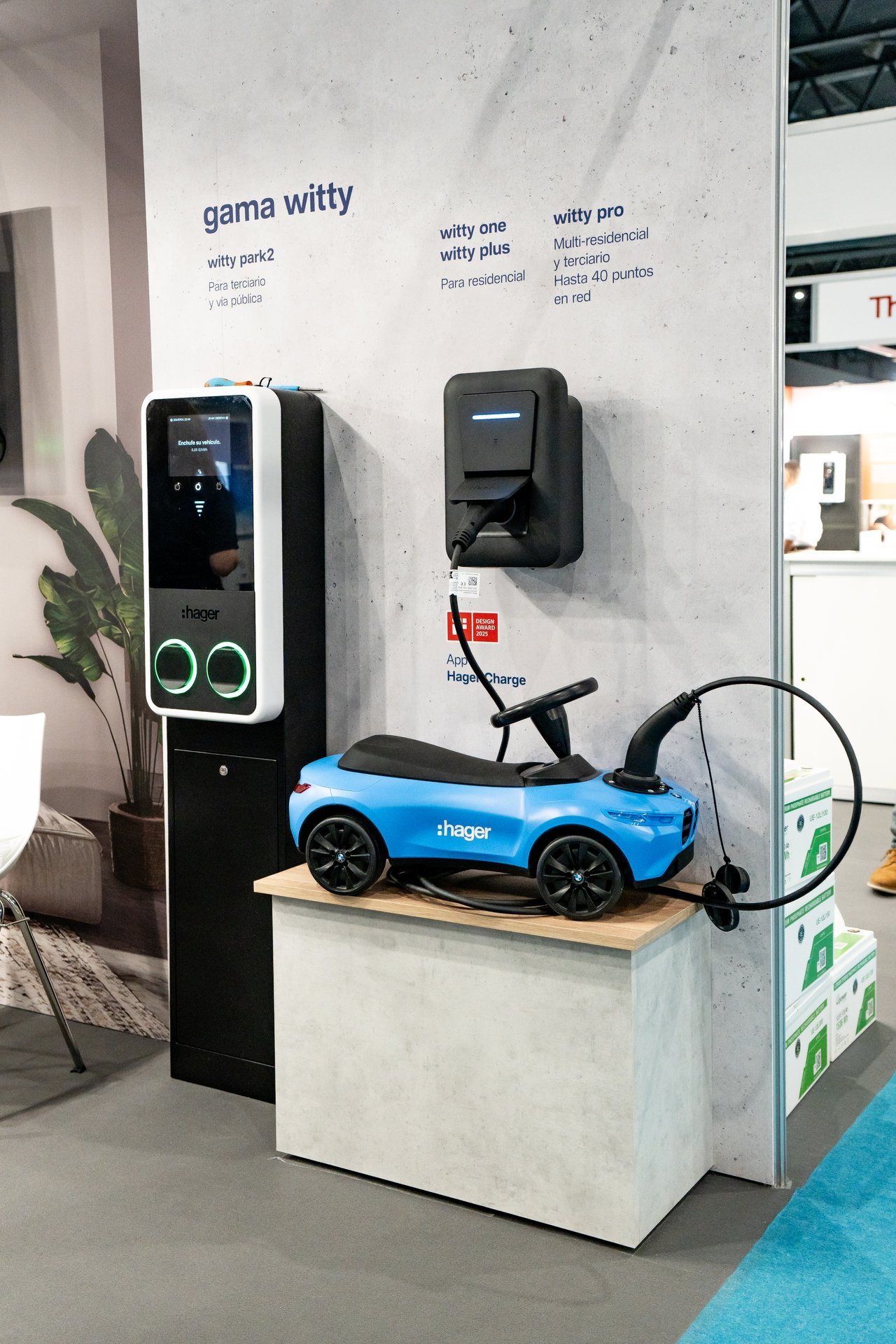 Stand de Hager en Efintec con cargadores Witty para vehículos eléctricos. Un coche de juguete azul está conectado a un cargador.