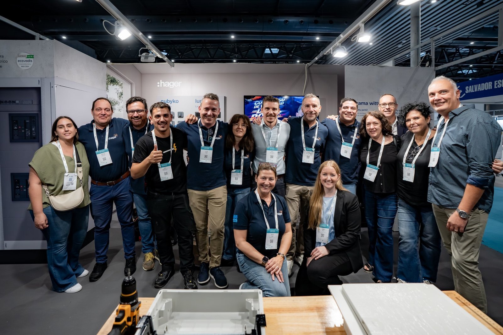 Equipo de Hager posando sonriente en su stand de Efintec. Varios llevan polos azules con el logo de la marca.