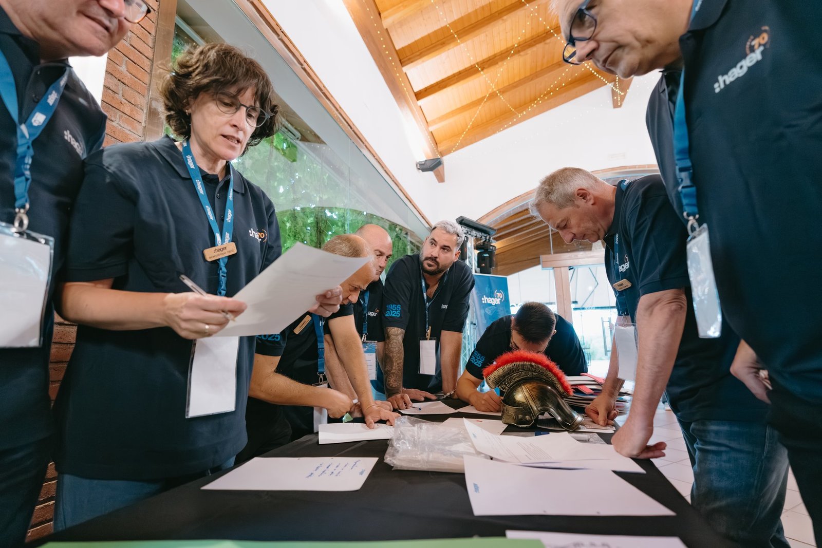 Grupo de empleados de Hager en un evento de teambuilding, reunidos alrededor de una mesa con papeles y un casco romano.