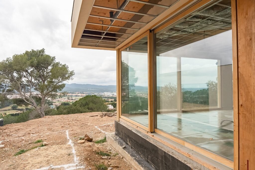 Lavabo de mármol blanco veteado integrado en encimera, con orificio para grifo. Ventana de madera con vista exterior borrosa.